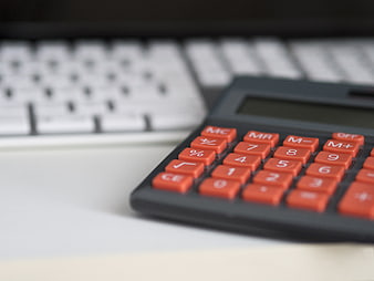 Close-up of calculator with orange buttons on desk