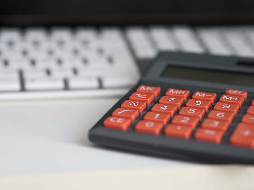Close-up of calculator with orange buttons on desk