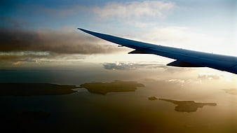 Airplane Wing Over Ocean Islands at Sunset