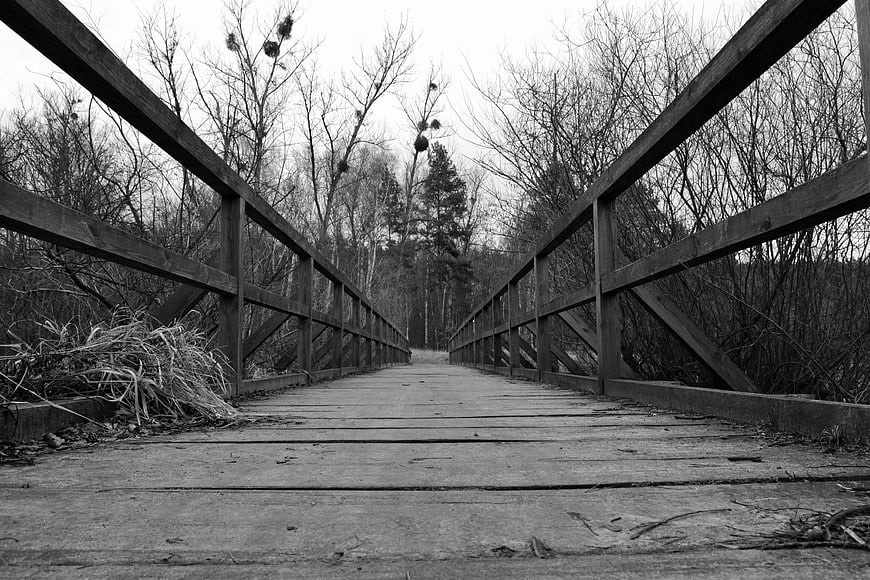 Black and white wooden bridge in a winter forest