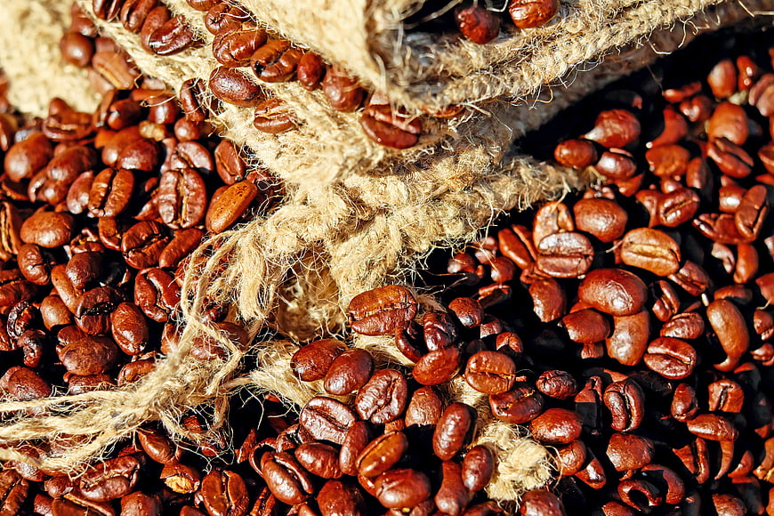 Close-up of roasted coffee beans spilling from a burlap sack