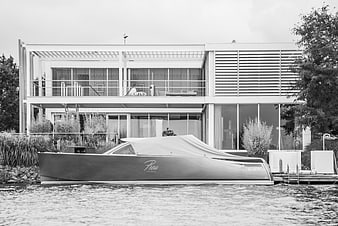 Modern waterfront house with covered boat docked in black and white