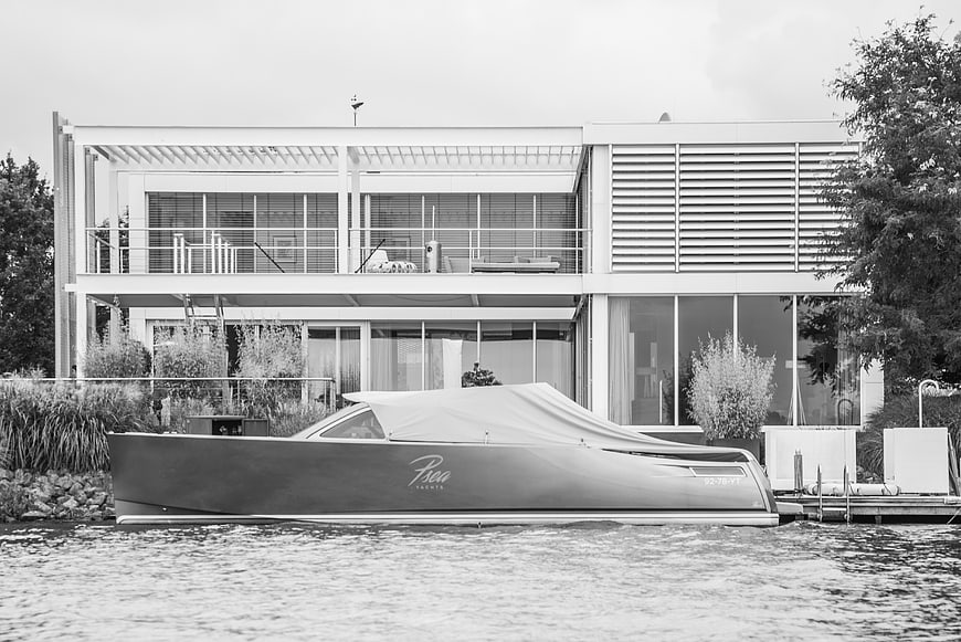 Modern waterfront house with covered boat docked in black and white