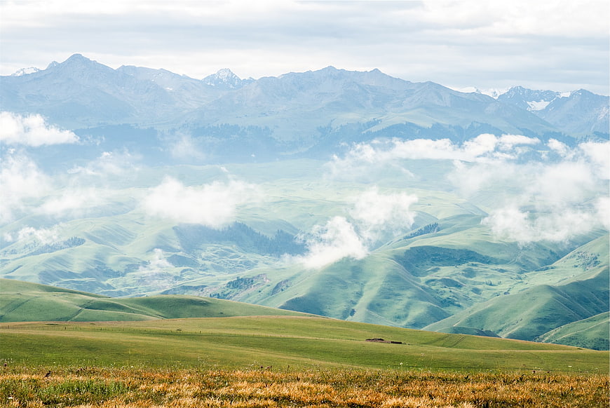 Misty green mountain landscape with rolling hills and clouds