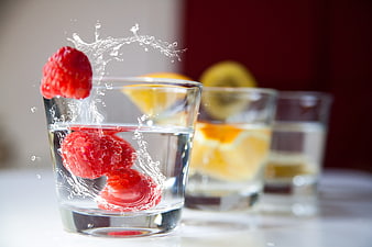 Fresh Raspberries Splashing into Glass of Water