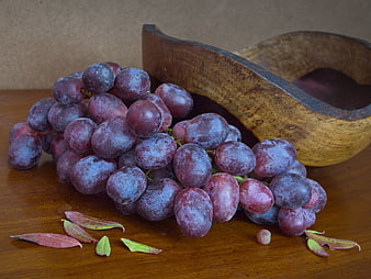 Ripe Purple Grapes Spilling from Wooden Bowl