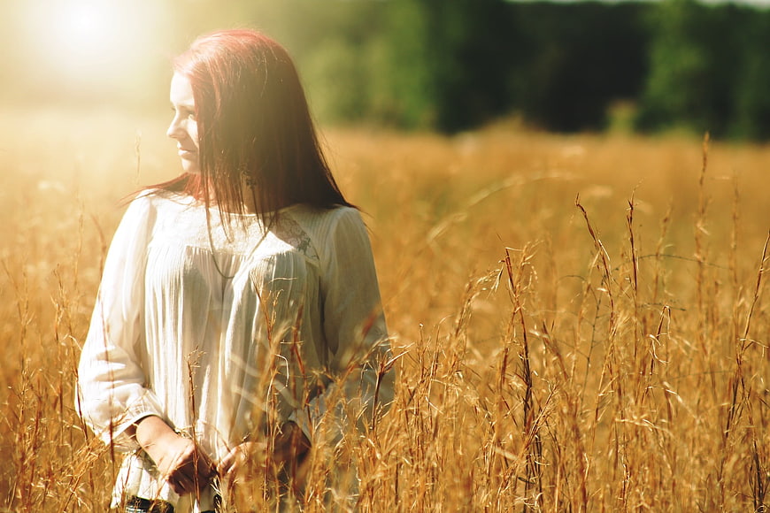 Woman in white dress standing in golden wheat field
