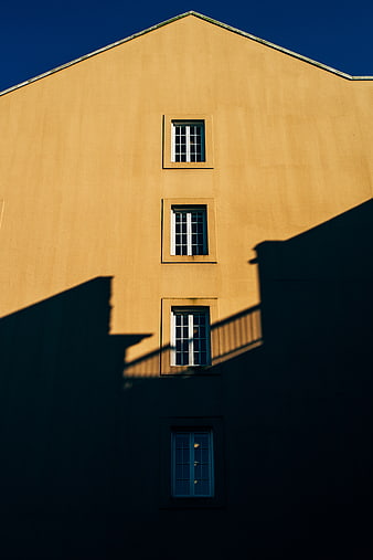 Minimalist Yellow Building Facade with Dramatic Shadows