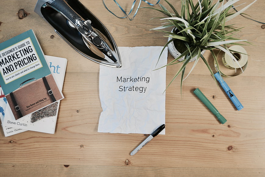 Marketing Strategy Flat Lay with Iron, Books, and Plant on Wood