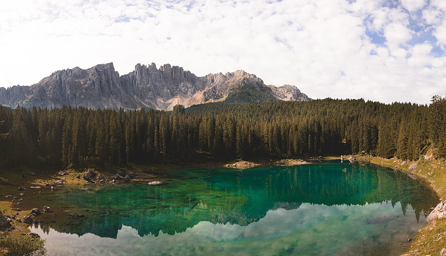 Turquoise alpine lake reflecting mountains and pine forest