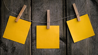 Three yellow sticky notes hanging on a clothesline with wooden clothespins