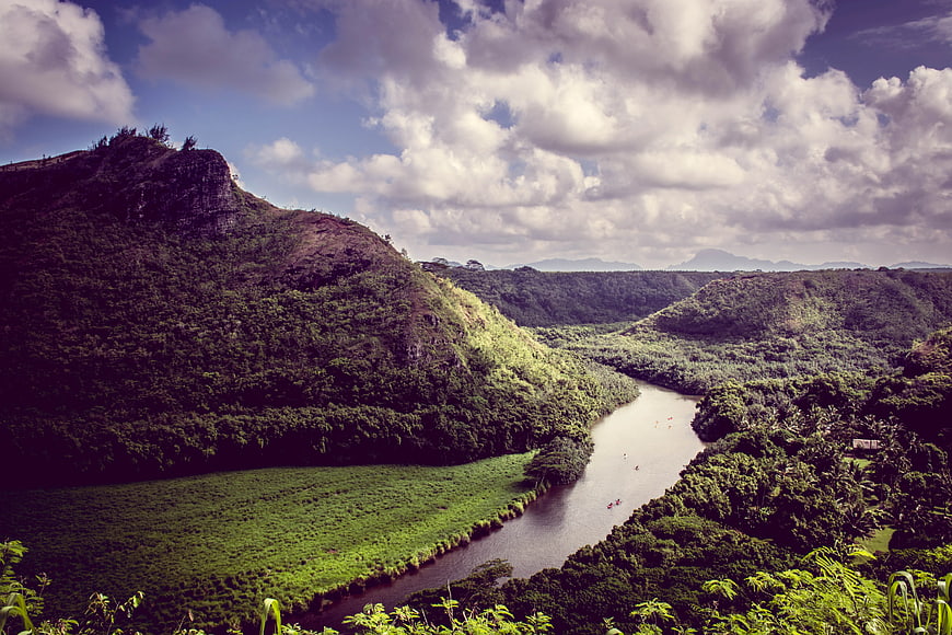 Lush Green River Valley with Mountain and Cloudy Sky