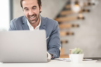 Happy businessman working on laptop in modern office