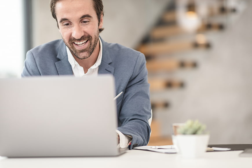 Happy businessman working on laptop in modern office