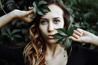 Young woman portrait holding green leaves in natural setting