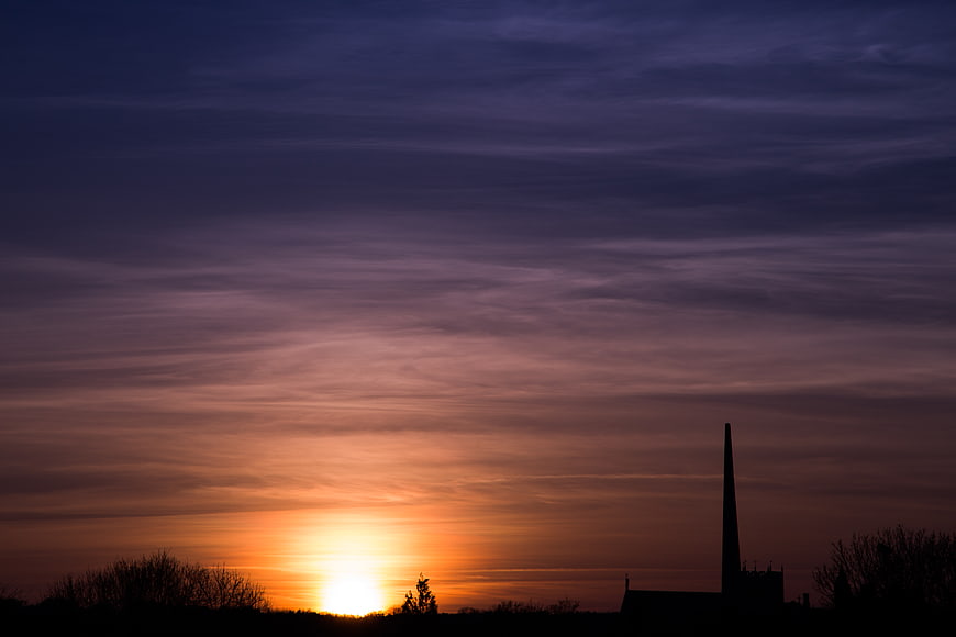 Silhouette of Church Steeple Against Vibrant Sunset Sky