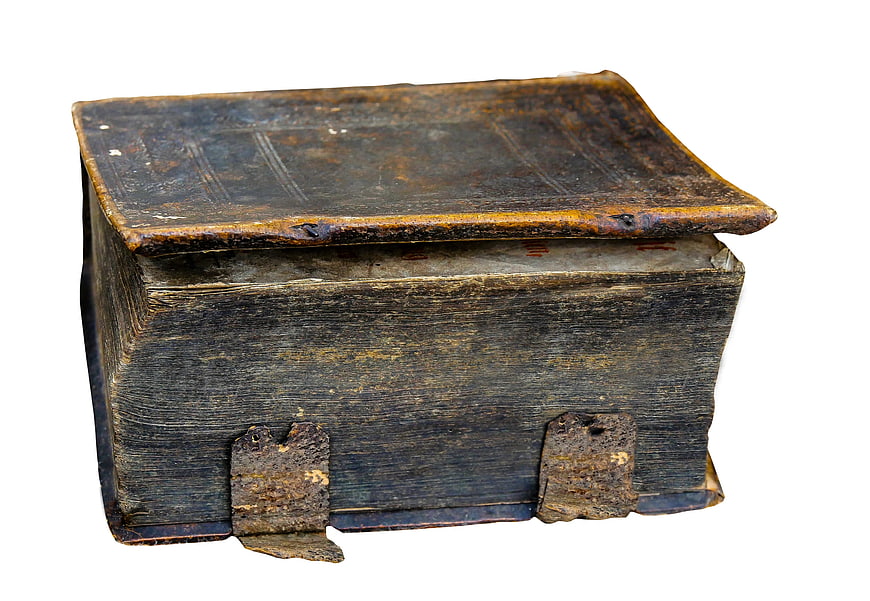 Ancient leather-bound book with metal clasps on white background