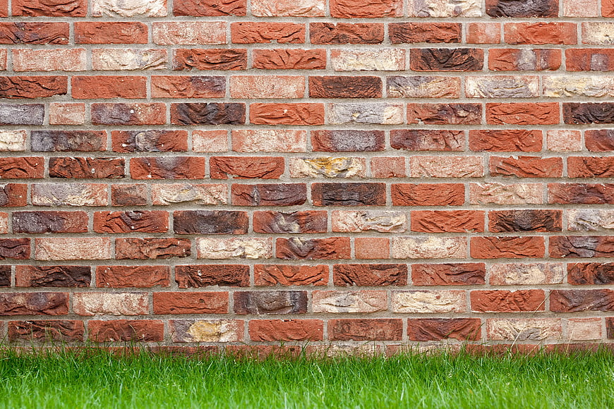 Textured Red Brick Wall with Green Grass Background