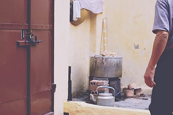 Man cooking outdoors with large pot and teapot