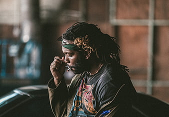 Man with dreadlocks smoking cigarette in urban setting