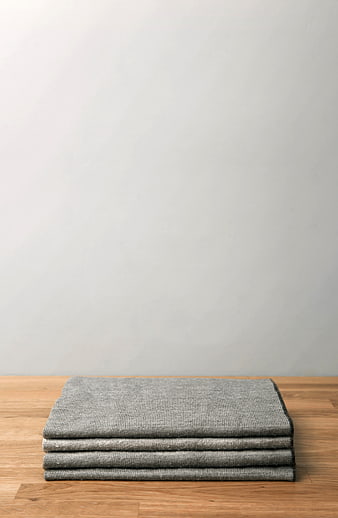 Stack of folded gray towels on wooden table with white background