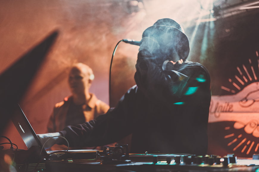 DJ performing live on stage with smoke and stage lights