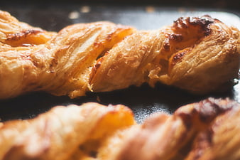 Close-up of golden baked twisted pastry on a dark surface