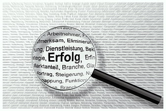 Magnifying glass focusing on German word Erfolg meaning success