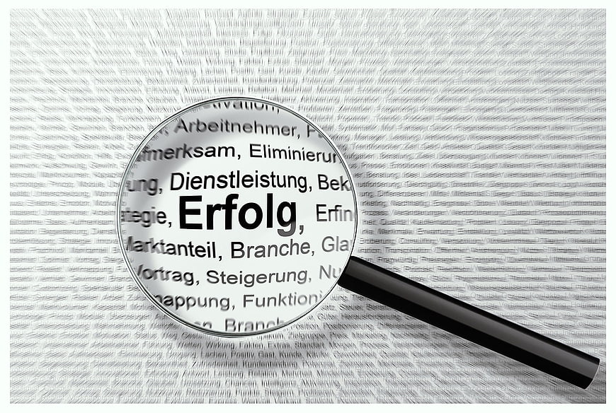 Magnifying glass focusing on German word Erfolg meaning success