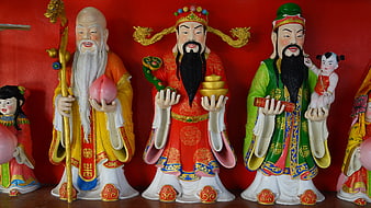 Traditional Chinese Deity Statues Displayed Against Red Background