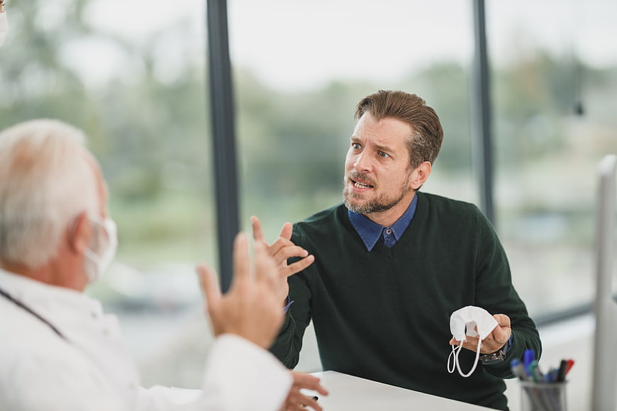 Upset male patient arguing with doctor in clinic