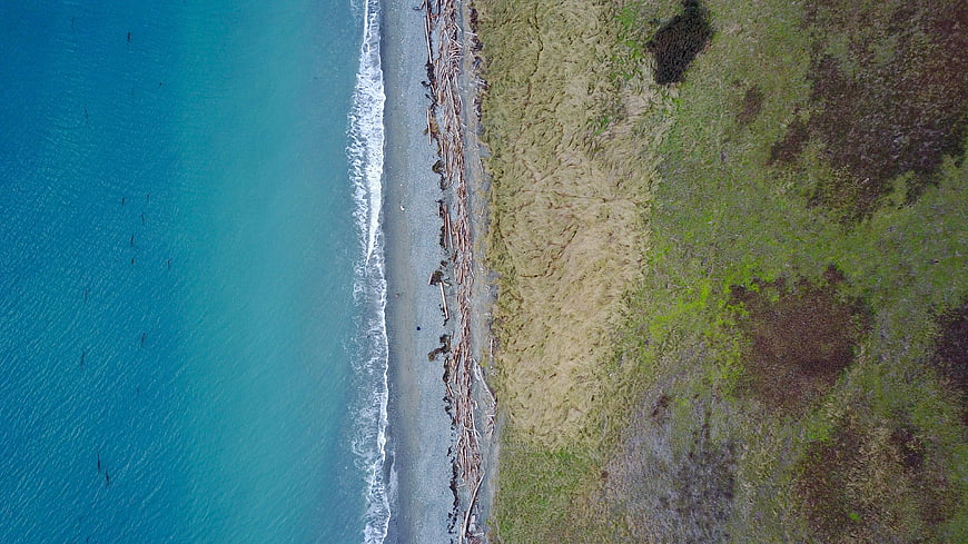 Aerial View of Turquoise Ocean Meeting Sandy Beach and Grassland