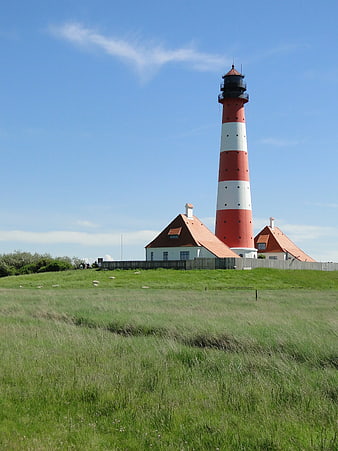 Red and White Lighthouse on Green Coastal Hill
