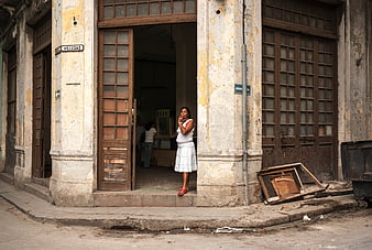 Woman in white dress standing in doorway of old Havana building