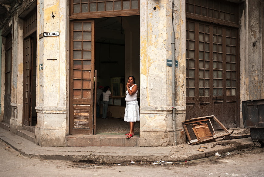 Woman in white dress standing in doorway of old Havana building
