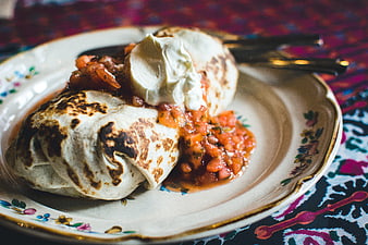 Close-up of grilled burrito with salsa and sour cream