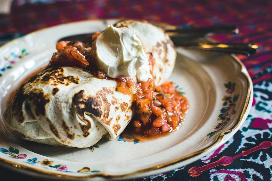 Close-up of grilled burrito with salsa and sour cream