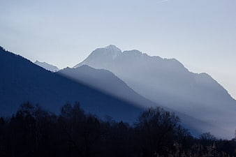 Misty Mountain Landscape with Sunbeams and Silhouetted Trees