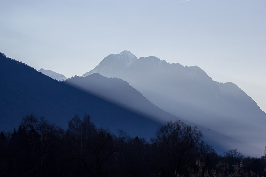 Misty Mountain Landscape with Sunbeams and Silhouetted Trees