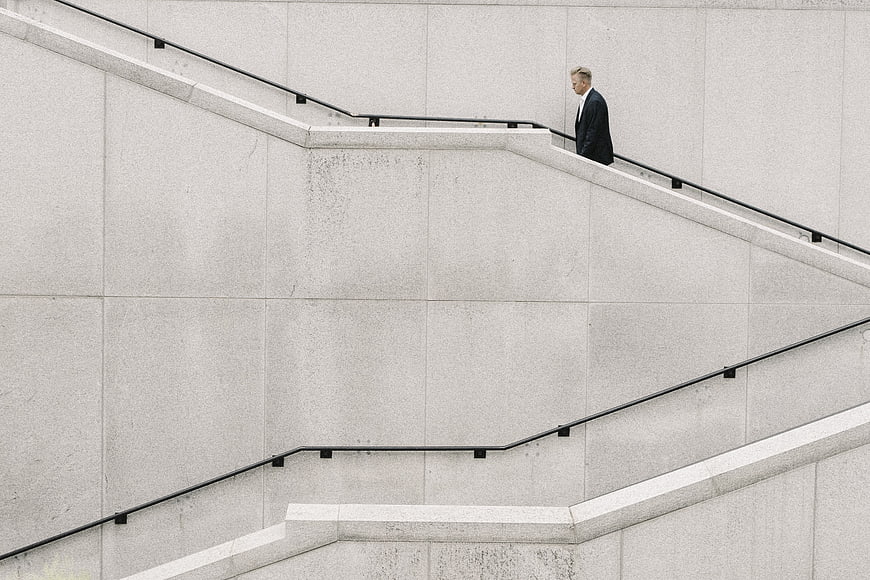 Man in Suit Walking Down Minimalist Concrete Stairs