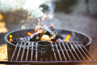 Black enamel camping mug on fire pit grill grate