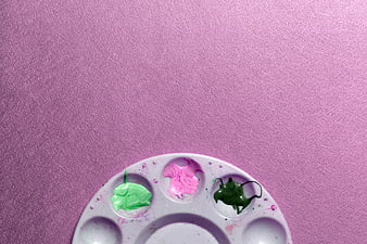 Paint Palette with Pink and Green Paint on Purple Background
