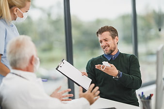 Upset male patient arguing with doctor and nurse in clinic