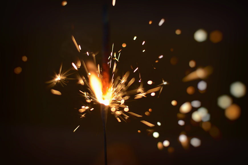 Burning Sparkler with Golden Sparks and Bokeh Background
