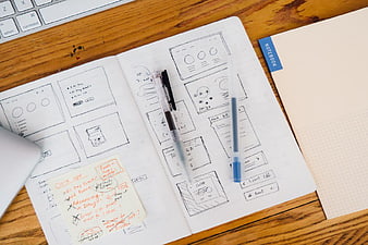 Hand-drawn wireframe sketches in notebook on wooden desk