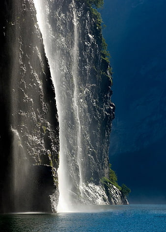 Majestic waterfall cascading down a steep cliff into a fjord