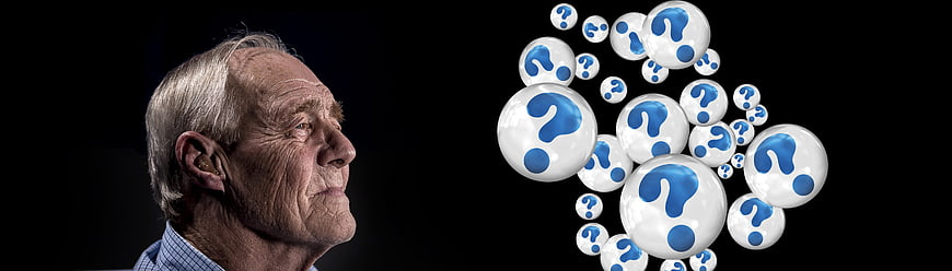Senior man looking at floating question mark bubbles