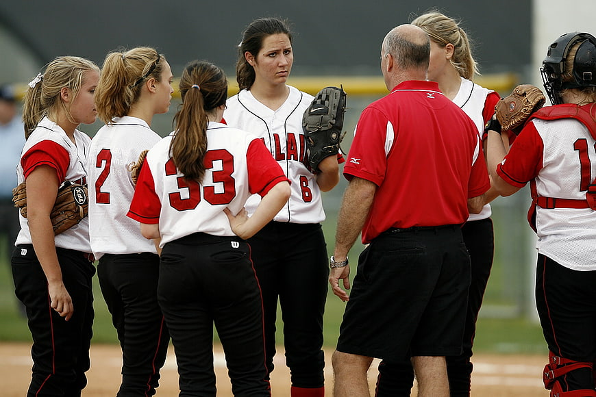 Female Softball Team Discussing Strategy With Coach On Field