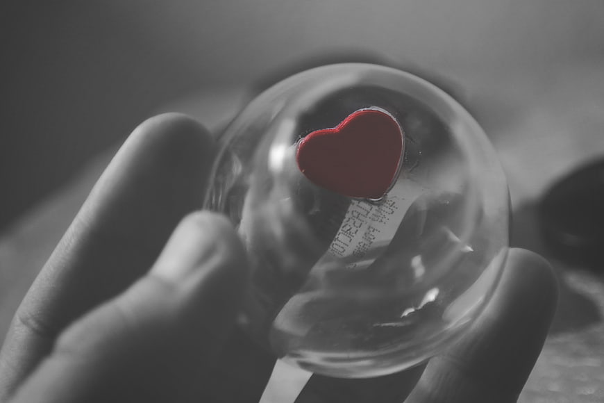 Hand holding glass heart with selective color