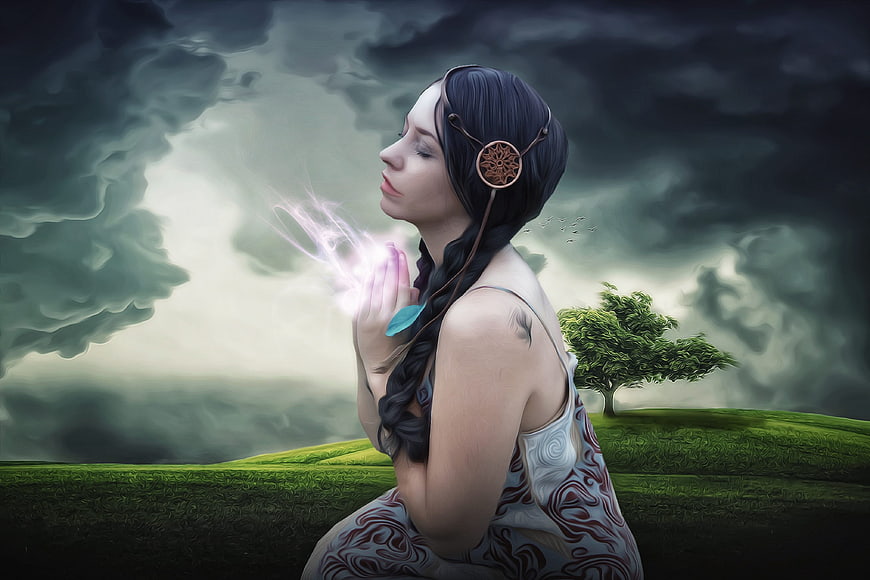 Fantasy woman praying with glowing hands in stormy landscape